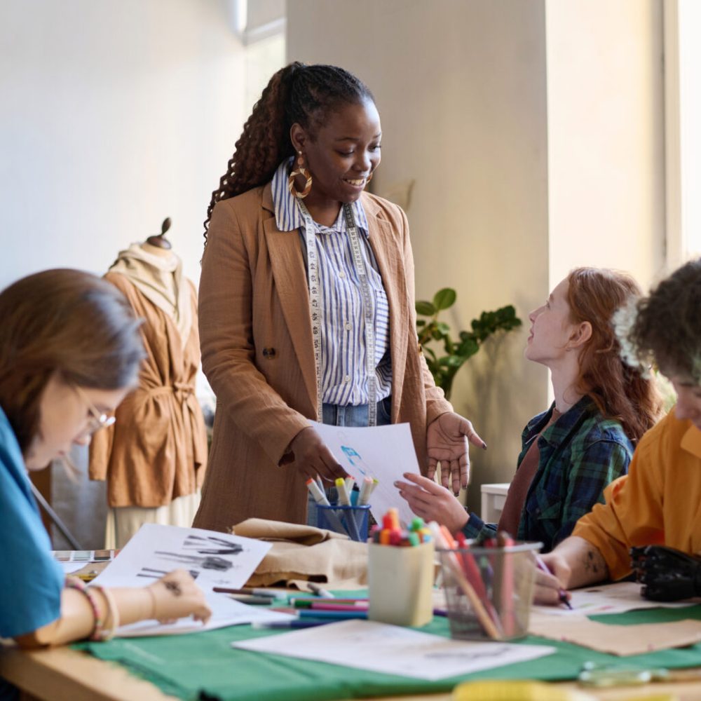 Portrait of smiling African American woman as teacher in tailoring and clothing design class for girls