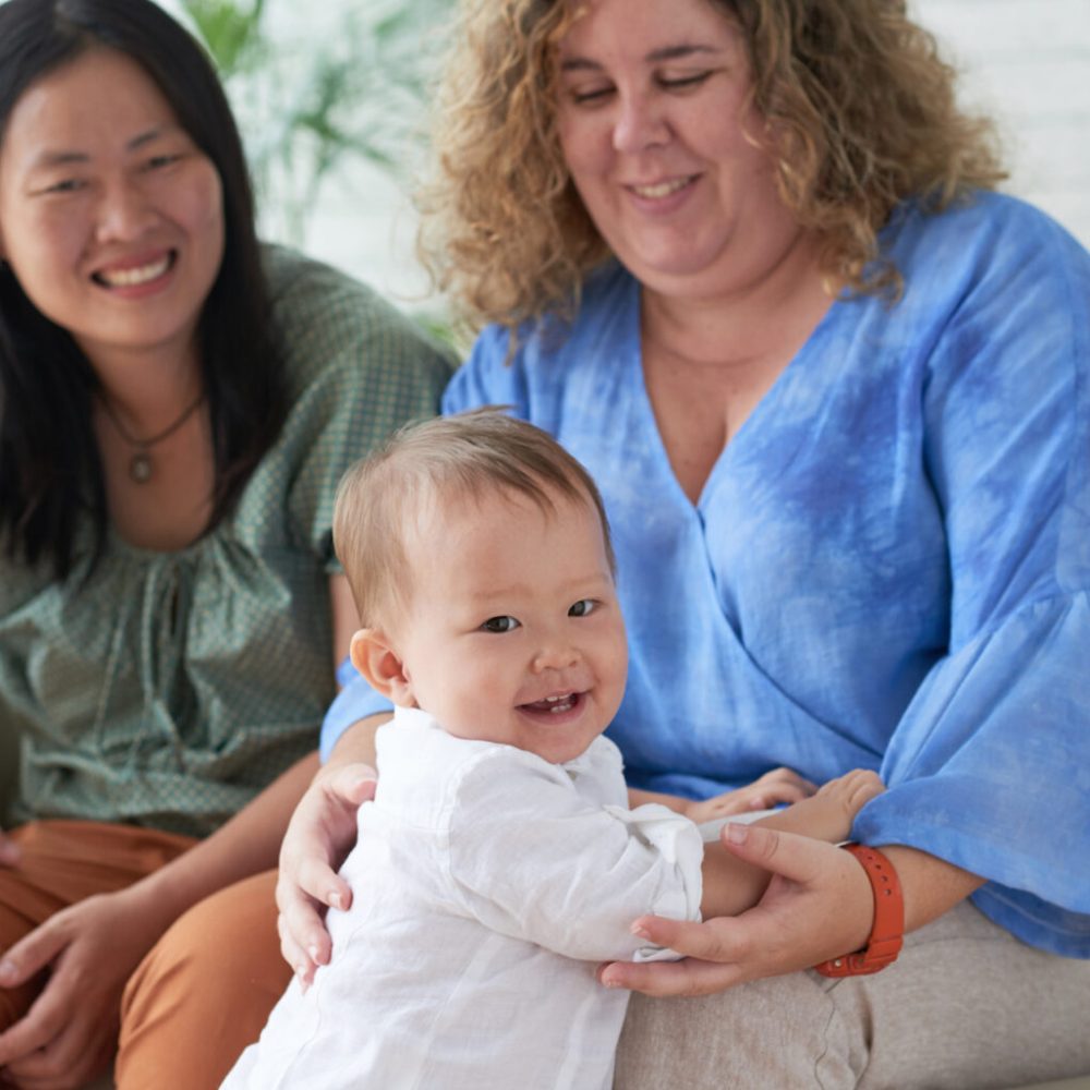 Happy little mixed-raced boy with his two mothers