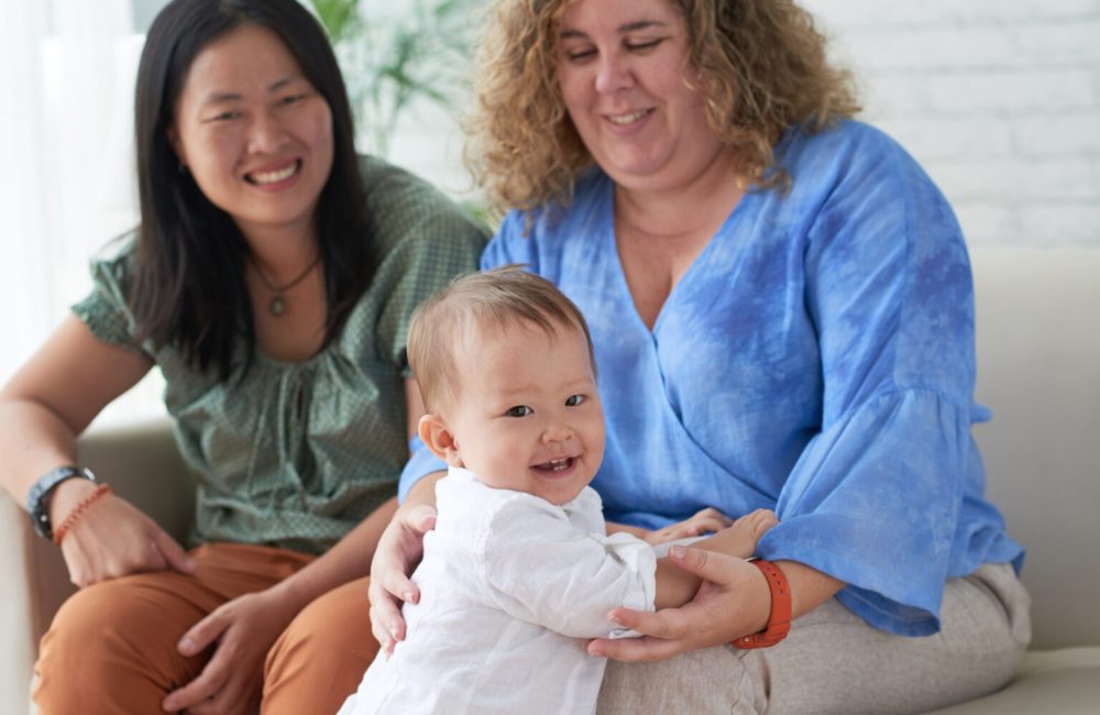 Happy little mixed-raced boy with his two mothers